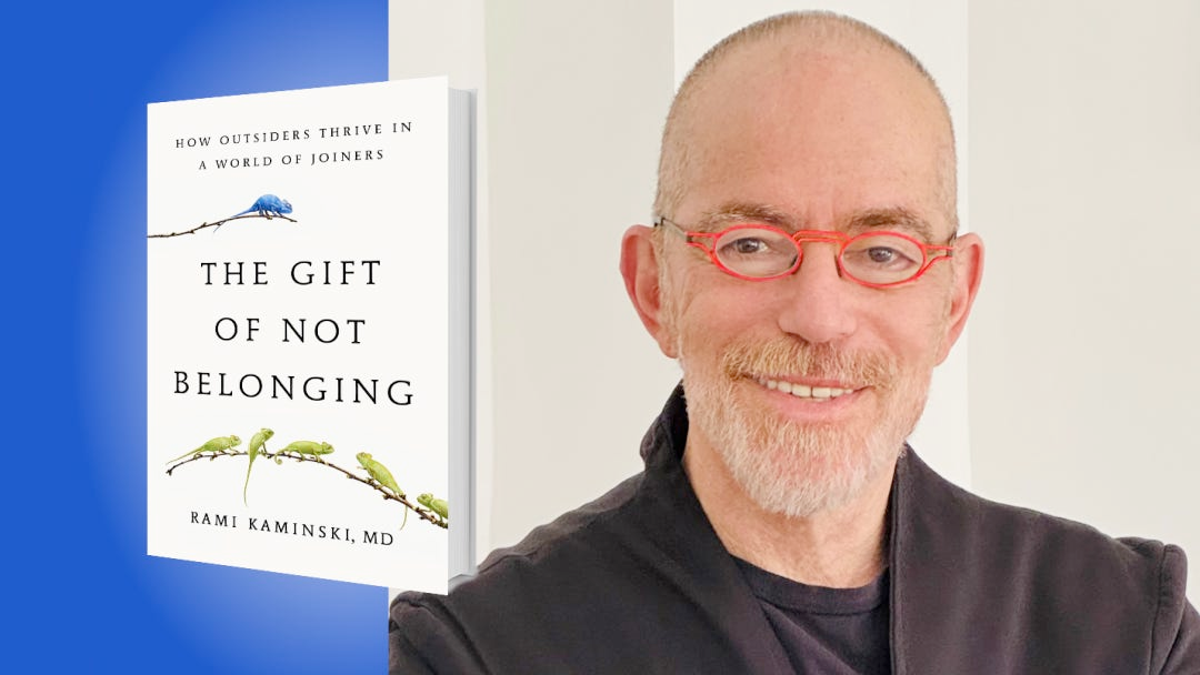 Cover of the book "The Gift of Not Belonging" by Rami Kaminski, MD, next to a portrait of the author wearing red glasses and smiling.